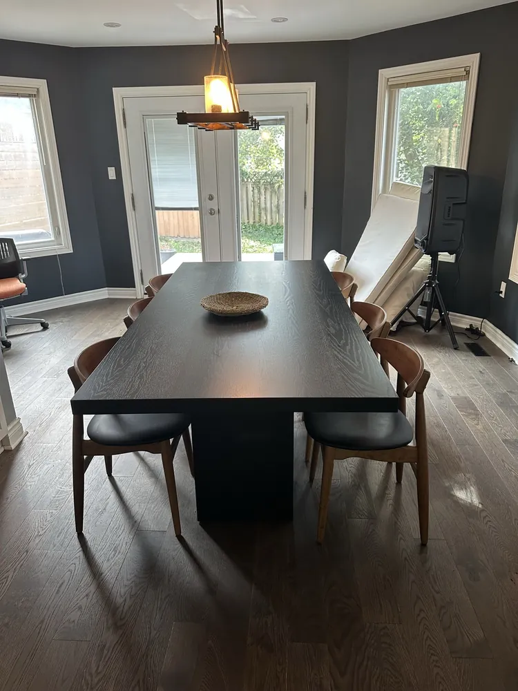 Before: a dining room with a black oak table and walnut chairs, and a speaker stand in the corner.